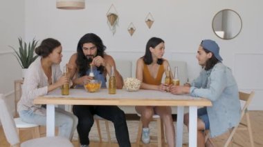 friends are sitting at the table, where a guy comes and brings a laptop, puts it on the table and drops a bottle of beer that spills