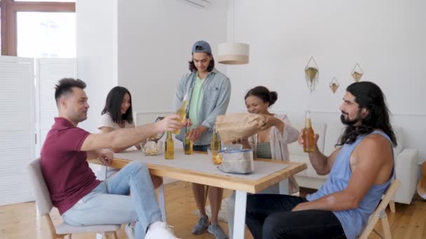 Хлопець Оточений Друзями Відкриває Пляшку Пива Дівчата Вливають Чіпси Миску — стокове відео