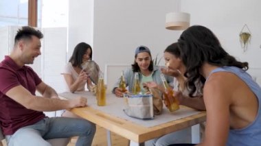friends of different ethnicity communicate eating chips drinking beer at the table