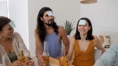 3 guys and 2 girls play leaves on their foreheads in a game of guessing who I am