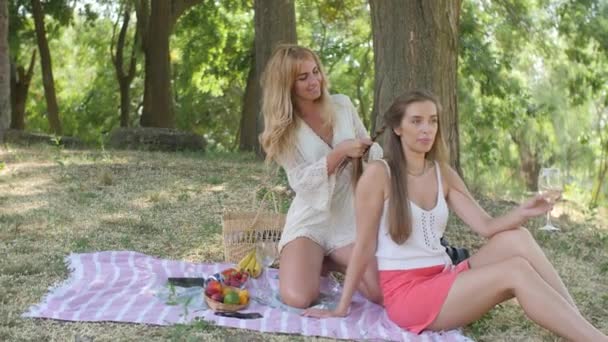 Girls Picnic Park Girl White Overalls Twists Her Girlfriends Pigtails — Vídeo de Stock