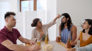 dark-skinned girl helps to stick a piece of paper on the guys forehead for playing who am I