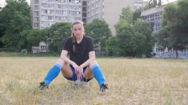the girl sits on the ball exhales and looks at the camera