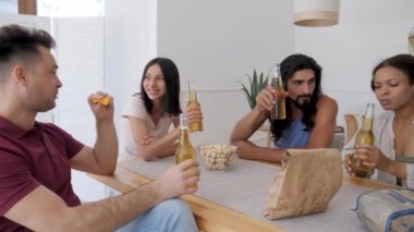a group of friends of guys and girls sit at the table chatting drinking beer eating chips