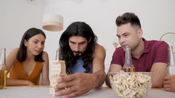 Guy Long Hair Surrounded Friends Rearranges Wand Concentration Game Jenga — Vídeo de stock