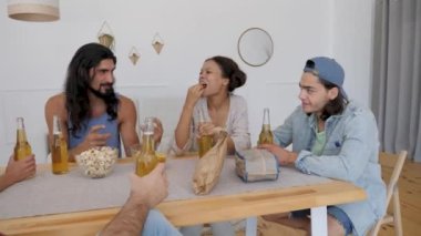 a group of friends sits at the table, a guy with long hair tells the rest of the story to his society