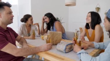 a group of friends sits at the table, a guy with long hair tells the rest of the story to his society