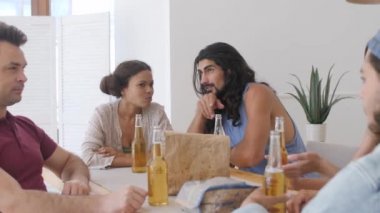 Koyu tenli bir kız ve uzun saçlı bir adam masadaki diğer arkadaşları tartışıyor.