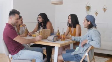 a group of friends sits at the table, a guy with long hair tells the rest of the story to his society