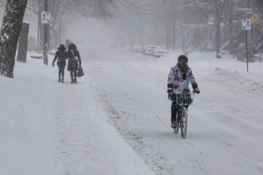Montreal, CA, 25 Şubat 2022: Kar fırtınası sırasında Laurier Caddesi 'nde bisiklet süren kadın