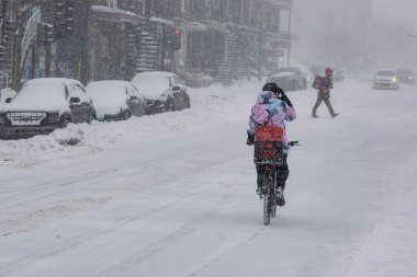 Montreal, CA, 25 Şubat 2022: Kar fırtınası sırasında Laurier Caddesi 'nde bisiklet süren kadın