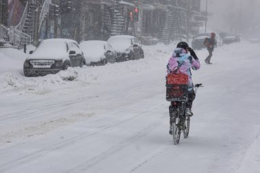 Montreal, CA, 25 Şubat 2022: Kar fırtınası sırasında Laurier Caddesi 'nde bisiklet süren kadın