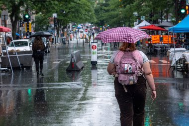 Montreal, CA - 12 Haziran 2022: Mont-Royal Caddesi 'ndeki insanlar yağmur ve fırtına sırasında şemsiye tutuyorlar