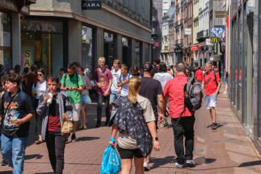 Amsterdam, The Netherlands - 23 June 2022: People walking on narrow street with many stores