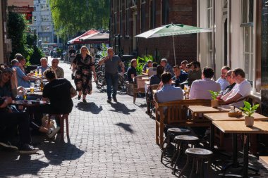 Amsterdam, The Netherlands - 22 June 2022: People eating at a restaurant on paved street