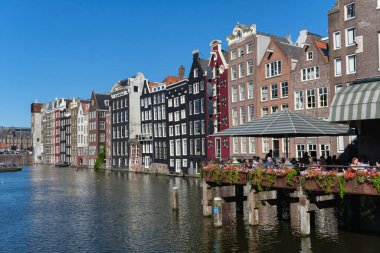 Amsterdam, Hollanda - 22 Haziran 2022: Damrak limanındaki bir restoranda yemek yiyen insanlar