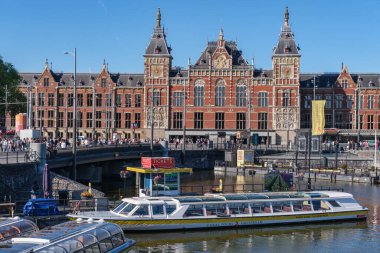 Amsterdam, Hollanda - 22 Haziran 2022: Damrak Kanalı 'nda turist botu, Amsterdam Merkez İstasyonu arka planda