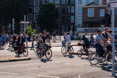 Amsterdam, Hollanda - 22 Haziran 2022: Damrak Caddesi 'nde bisiklet süren insanlar