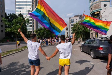Montreal, CA - 7 August 2022: Two young men holding hands take part in spontaneous gay pride march after official pride parade was cancelled