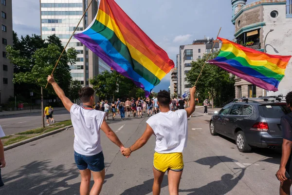 Montreal, CA - 7 August 2022: Two young men holding hands take part in spontaneous gay pride march after official pride parade was cancelled