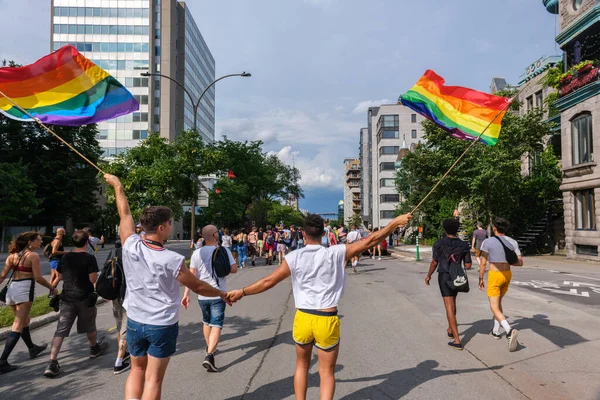 Montreal, CA - 7 August 2022: Two young men holding hands take part in spontaneous gay pride march after official pride parade was cancelled