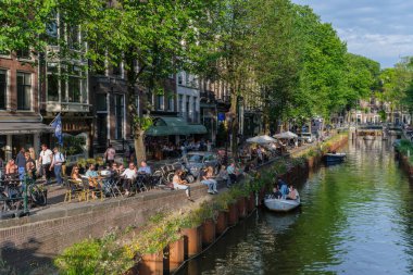 Amsterdam, The Netherlands - 21 June 2022: Boats on Amsterdam Canal at sunset