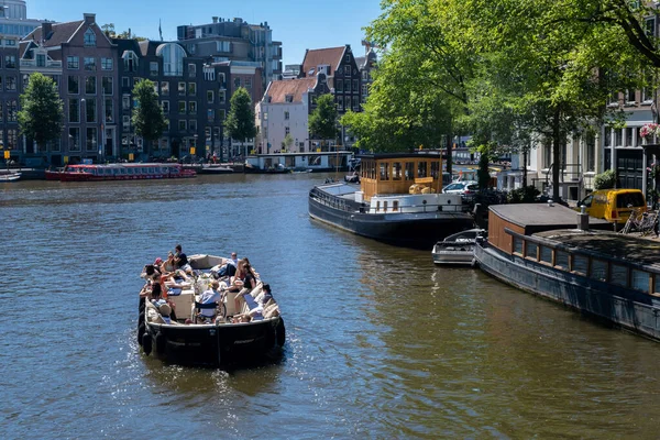 Amsterdam, The Netherlands - 21 June 2022: Tour boat and Houseboats on Amstel River