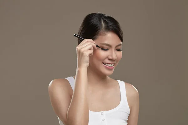 Mujer asiática aplicando eye liner — Foto de Stock