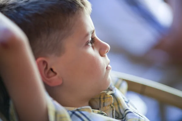 Nadenkend kind zit met de handen achter het hoofd — Stockfoto