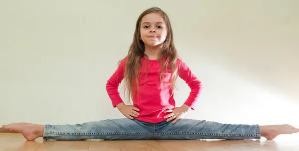 Pequeña niña se sienta en un splits — Foto de Stock