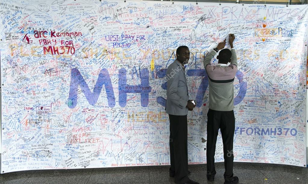 KUALA LUMPUR INTERNATIONAL AIRPORT - MARCH 17: Unidentified men write messages and prayers for Malaysia Airlines Boeing 777-200ER MH370 on March 17, 2014 in KLIA, Sepang, Malaysia.