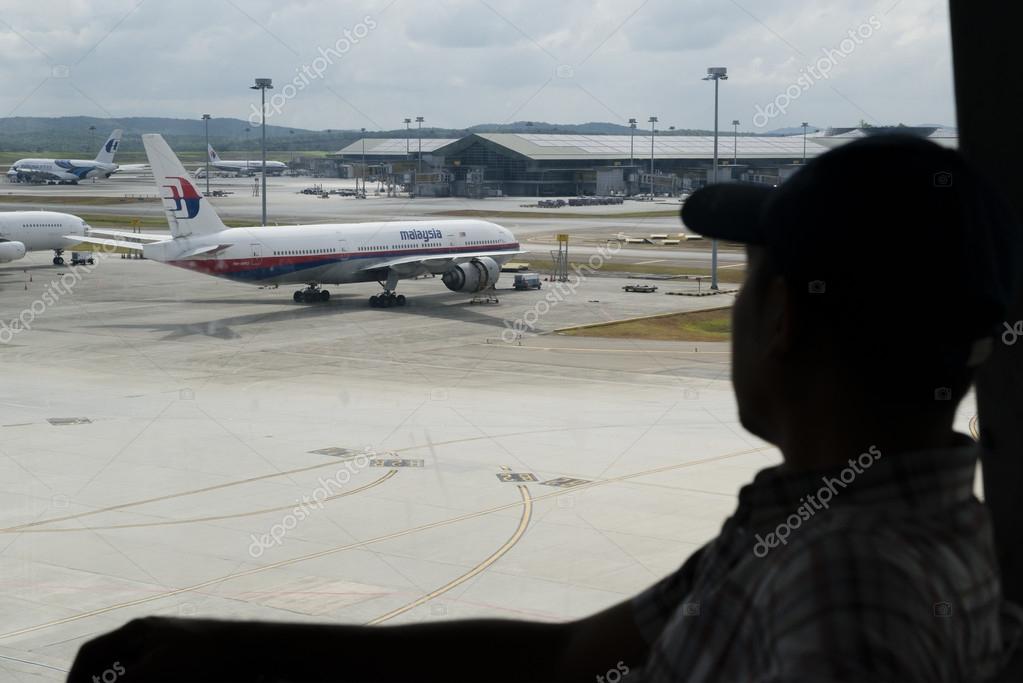 KUALA LUMPUR INTERNATIONAL AIRPORT - MARCH 17: Silhouette of a man with Malaysia Airlines Boeing 777-200ER MH370 in the background on March 17, 2014 in KLIA, Sepang, Malaysia.