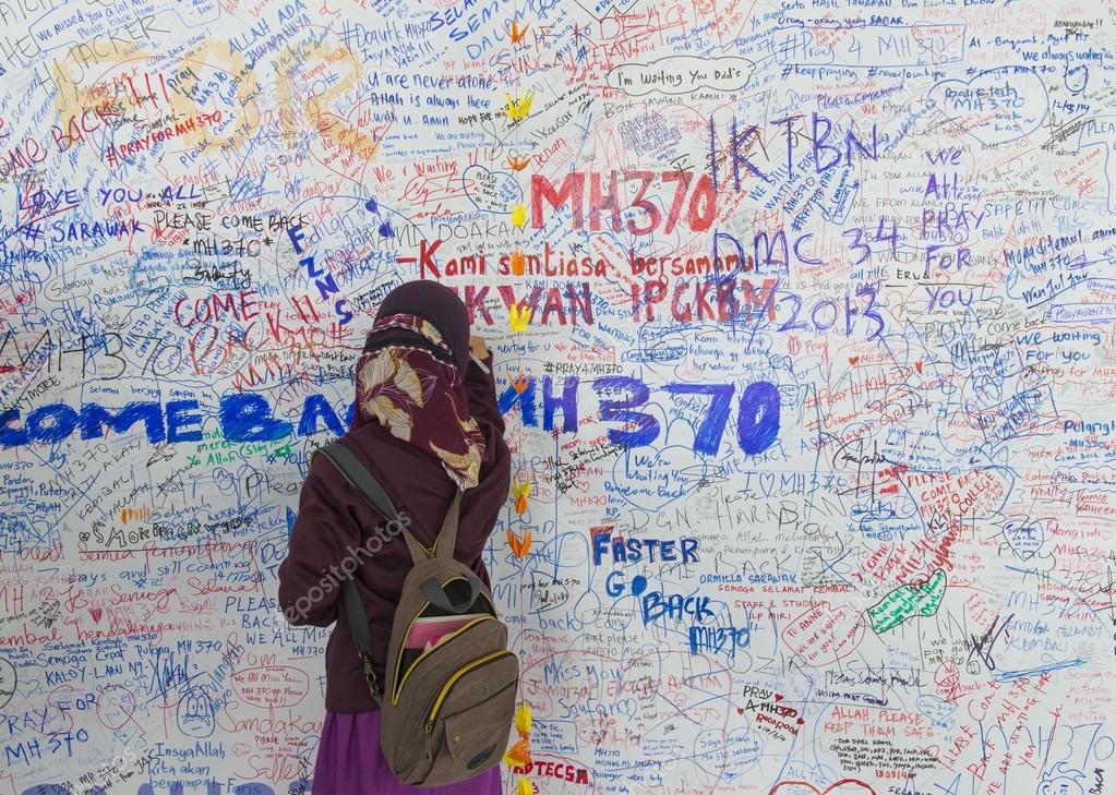 KUALA LUMPUR INTERNATIONAL AIRPORT - MARCH 17: Unidentified Muslim girl writes messages and prayers for Malaysia Airlines Boeing 777-200ER MH370 on March 17, 2014 in KLIA, Sepang, Malaysia.