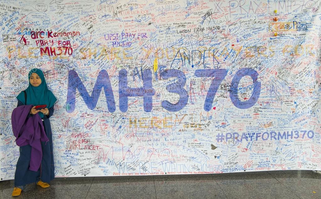 KUALA LUMPUR INTERNATIONAL AIRPORT - MARCH 17: Unidentified Muslim girl poses in front of a banner in support of Malaysia Airlines Boeing 777-200ER MH370 on March 17, 2014 in KLIA, Sepang, Malaysia.