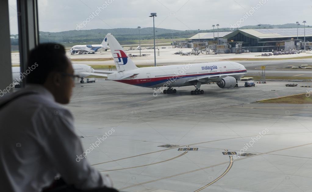 KUALA LUMPUR INTERNATIONAL AIRPORT - MARCH 17: Silhouette of a man with Malaysia Airlines Boeing 777-200ER MH370 in the background on March 17, 2014 in KLIA, Sepang, Malaysia.