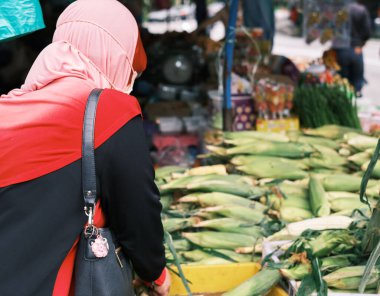 Yüz maskeli kimliği belirsiz Müslüman kadın Malezya, Pahang 'daki Cameron Highlands' ten taze sebze alıyor..