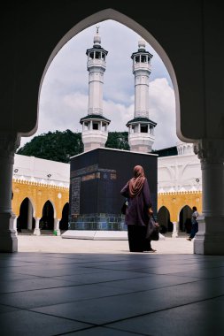 Tanımlanamayan Müslüman bir kadın bir Kaabah modelini izliyor..