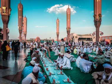SAUDI ARABIA-CIRCA 2019: Müslüman erkekler, Medine 'deki Nabawi Camii' nin yerleşkesinde gün batımında oruç tutmaya hazırlanıyorlar. Kapalı pastel renk filtresi uygulandı.