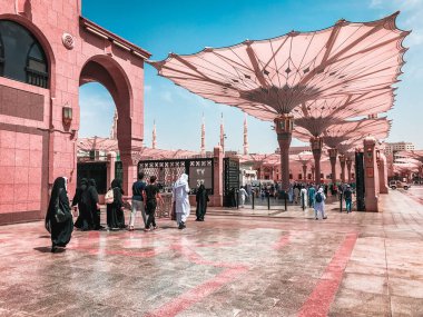AL MADINA, SAUDI ARABIA-CIRCA 2019: Müslüman hacılar Madinah 'ta öğle namazı için Mescid Nabawi Camii' ne girdiler. Suudi Arabistan. Kapalı pastel renk filtresi uygulandı.