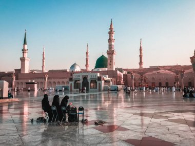 AL MADINAH, SAUDI ARABIA-CIRCA 2019: Nabawi Camii 'nin bileşiğinde başörtüsü içinde kadın hacılar dinleniyor. Sessiz pastel renk filtresi uygulandı.