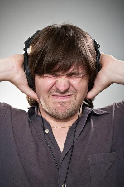 Człowiek zbyt głośno słuchać muzyki na słuchawkach — Zdjęcie stockowe