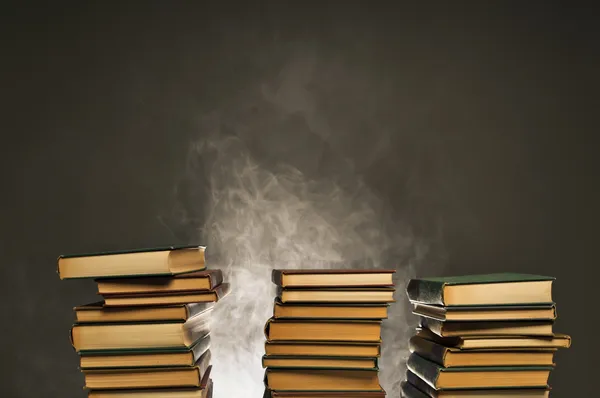 Stacked Books with Smoke Smoldering Behind Them — стоковое фото