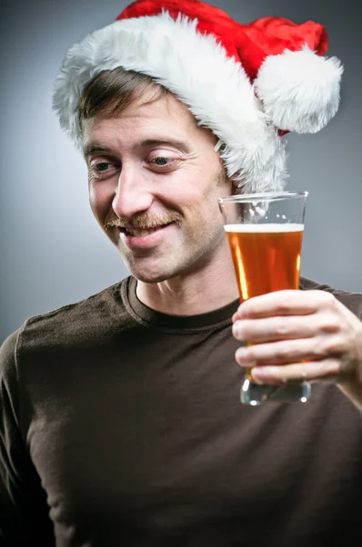 Homem vestindo chapéu de Santa relutantemente brindar com cerveja — Fotografia de Stock