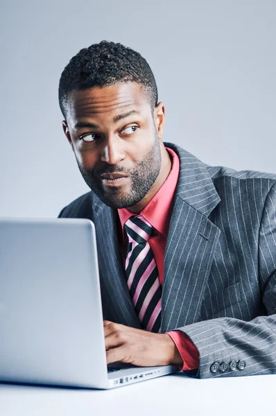 Jeune homme d'affaires afro-américain étant sournois sur ordinateur portable — Photo