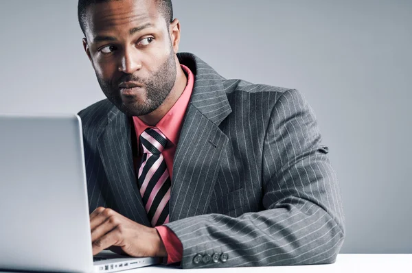 年轻的非洲裔美国商人正在鬼鬼祟祟在笔记本电脑上 — 图库照片
