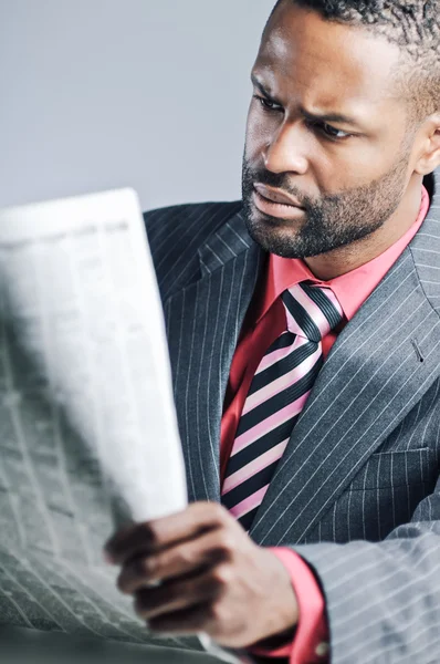 Молодой афроамериканский бизнесмен читает газету — стоковое фото