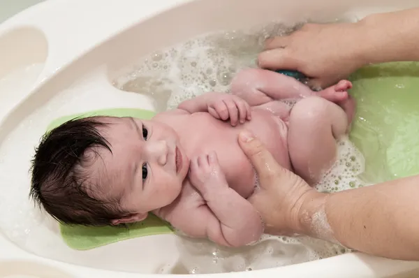 신생아 지 고 그의 첫 목욕 스톡 사진