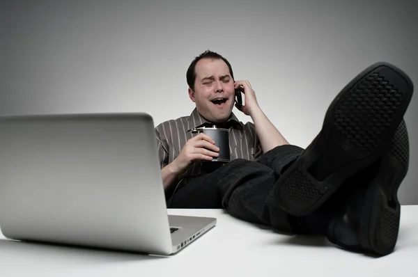 Slacker hablando por teléfono mientras bebe de un frasco en el trabajo —  Fotos de Stock