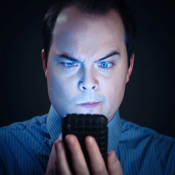 Homem assistindo quizzicamente algo no telefone inteligente — Fotografia de Stock