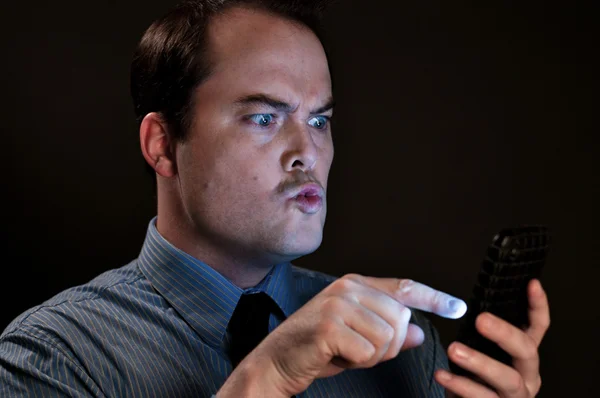 Homem assistindo quizzicamente algo no telefone inteligente — Fotografia de Stock